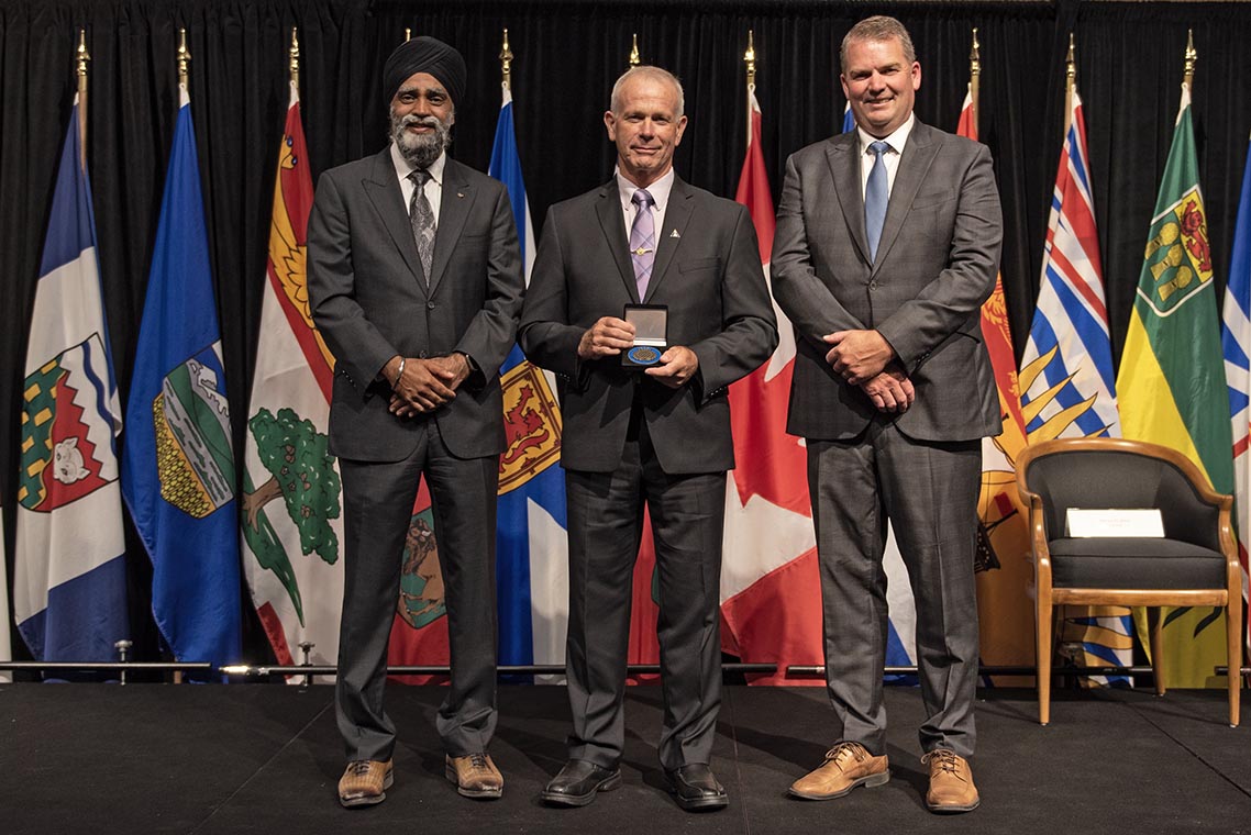 The Honourable Harjit S. Sajjan, President of the King’s Privy Council for Canada and Minister of  Emergency Preparedness (far left) and Minister responsible for the Pacific Economic  Development Agency of Canada, and the Honourable Bloyce Thompson, Deputy  Premier, Minister of Justice and Public Safety and Attorney General for Prince  Edward Island (far right) are pictured with the 2022 award recipient of the  Emergency Management Exemplary Service Award for the Outstanding Contribution  to Emergency Management category.