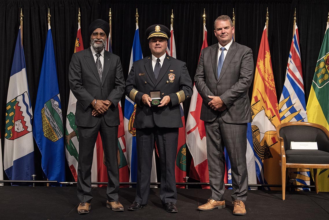 The Honourable Harjit S. Sajjan, President of the King’s Privy Council for Canada and Minister of  Emergency Preparedness (far left) and Minister responsible for the Pacific  Economic Development Agency of Canada, and the Honourable Bloyce Thompson, Deputy  Premier, Minister of Justice and Public Safety and Attorney General for Prince  Edward Island (far right) are pictured with the 2022 award recipient of the  Emergency Management Exemplary Service Award for the Resilient Communities  category.